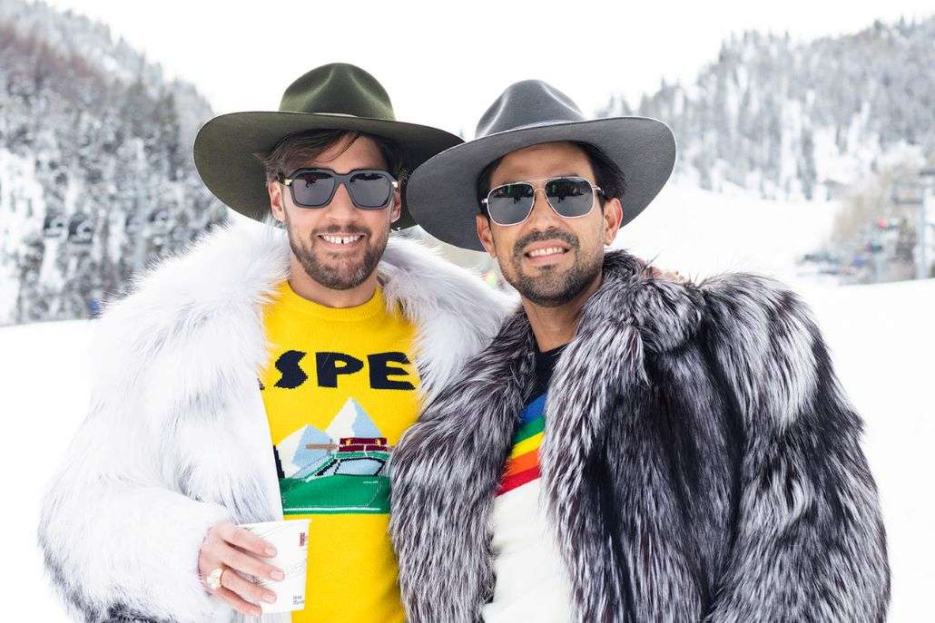 Two men wearing elegant fur coats and hats stand side by side for a photo, reflecting the essence of Aspen Style.
