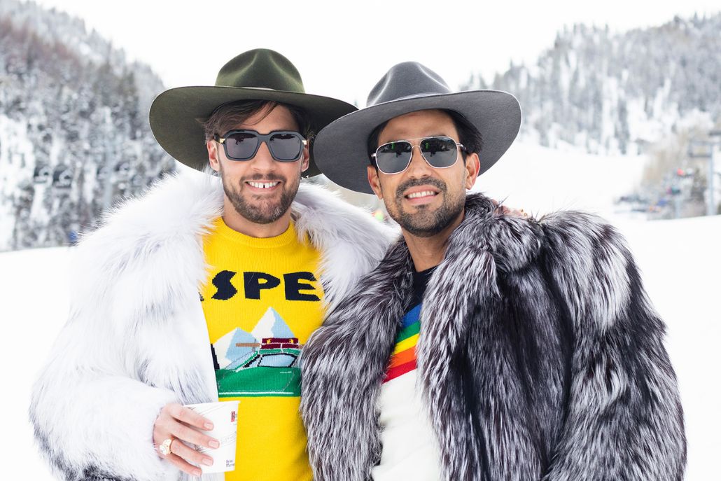 Two men wearing elegant fur coats and hats stand side by side for a photo, reflecting the essence of Aspen Style.