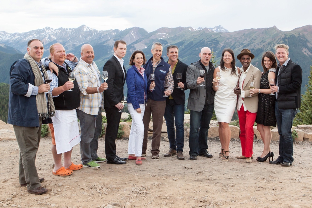 A group of people smiling and holding wine glasses, posing together at the Aspen Summer Activities Food & Wine Classic event.