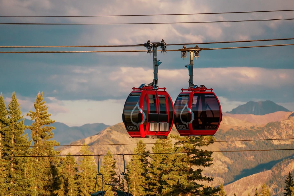 Two gondolas glide above the mountains, offering stunning views during a summer scenic ride in Aspen.