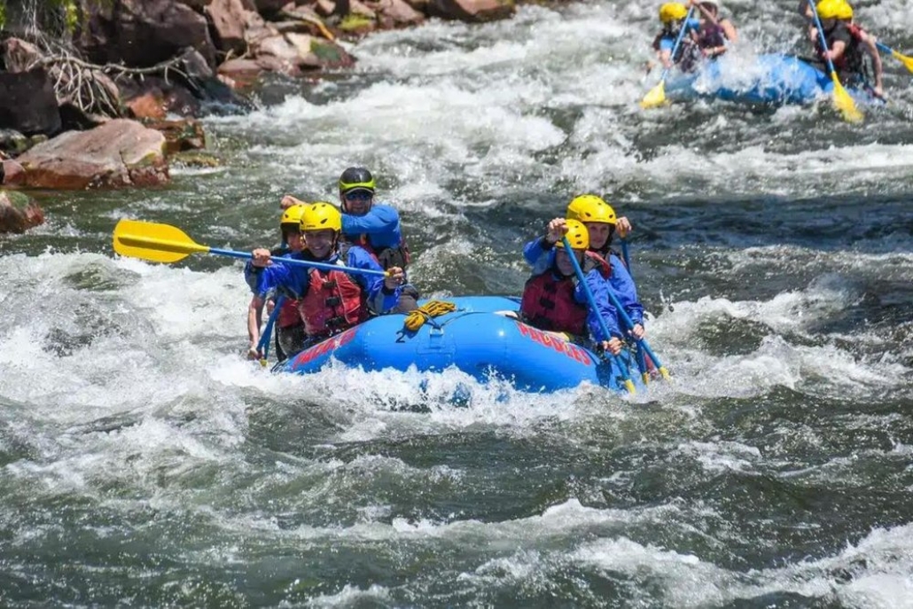 Rafting enthusiasts navigate a river, experiencing the excitement of Aspen adventure during summer.