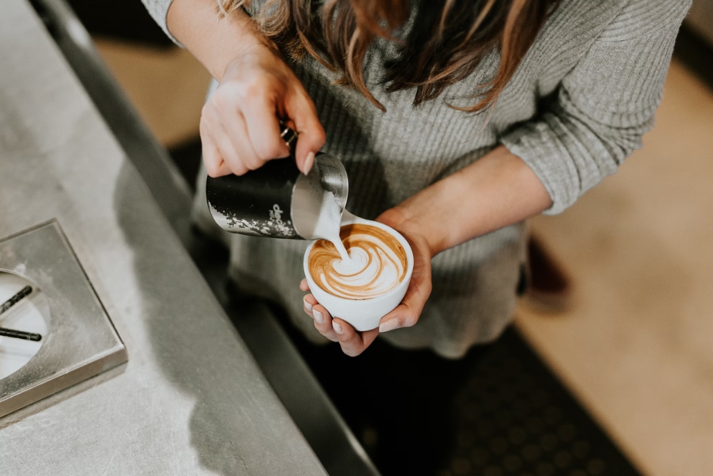 A woman elegantly pours coffee into a cup, showcasing the charm of Aspen's summer coffee shop scene.