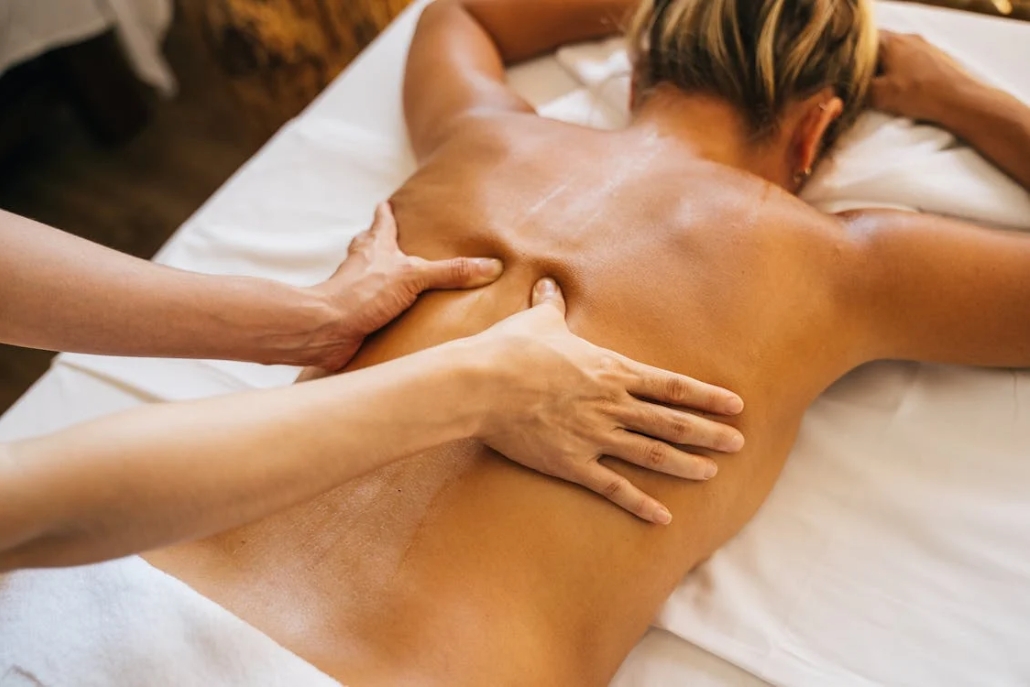 A woman relaxes with a back massage in a serene spa, emphasizing the luxury and tranquility of summer activities in Aspen.