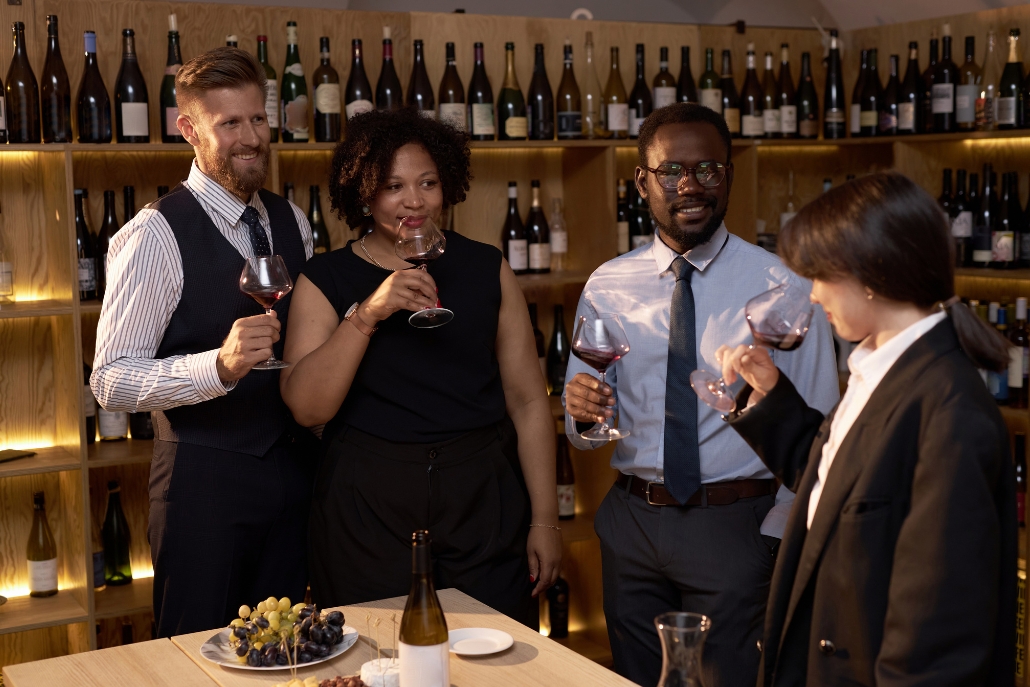A group of business professionals stand near a selection of wine bottles, showcasing summer wine tasting options in Aspen.