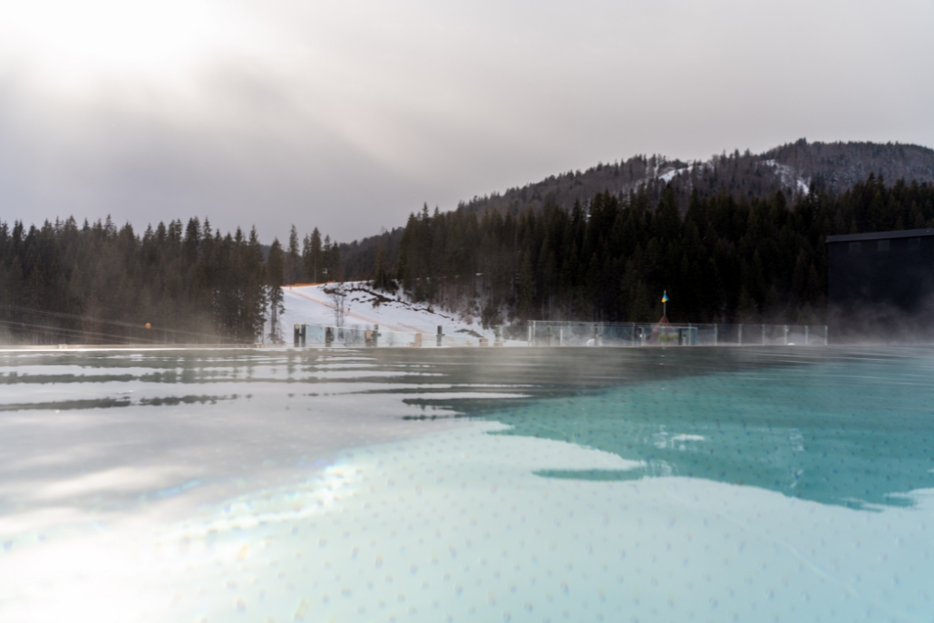 A picturesque pool with inviting water, set against a stunning mountain view, perfect for enjoying Aspen's winter hot springs.