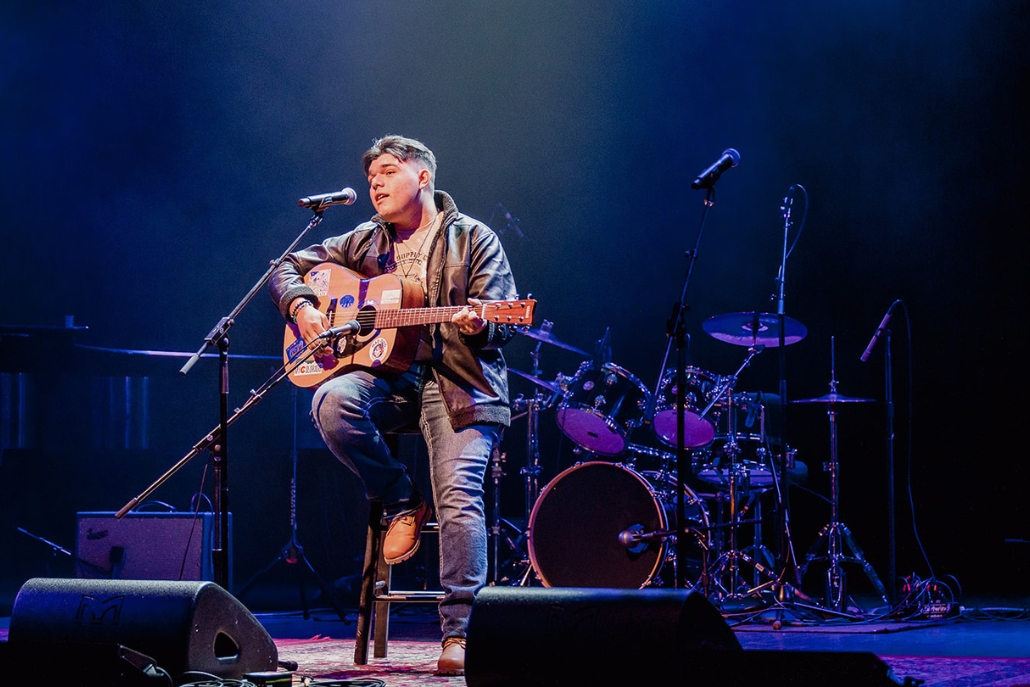 A man seated with an acoustic guitar, representing live music experiences available in Aspen during the winter season.