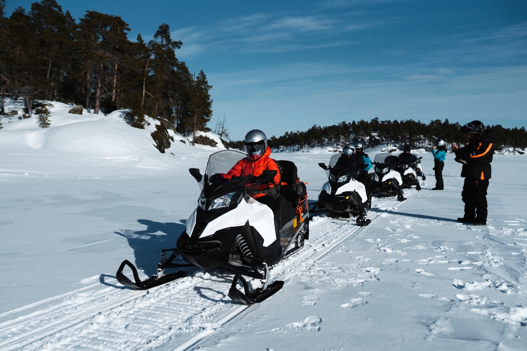 A group of people riding snowmobiles through a snowy landscape, showcasing winter activities in Aspen.