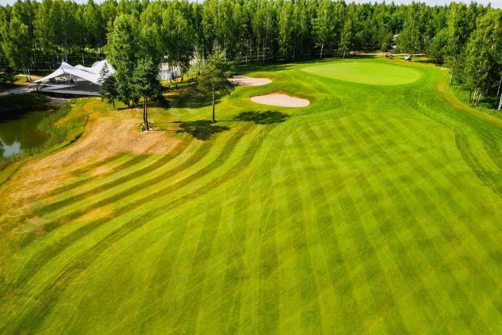 A picturesque golf course at Aspen Golf Club, highlighted by green grass and trees under a clear blue sky.