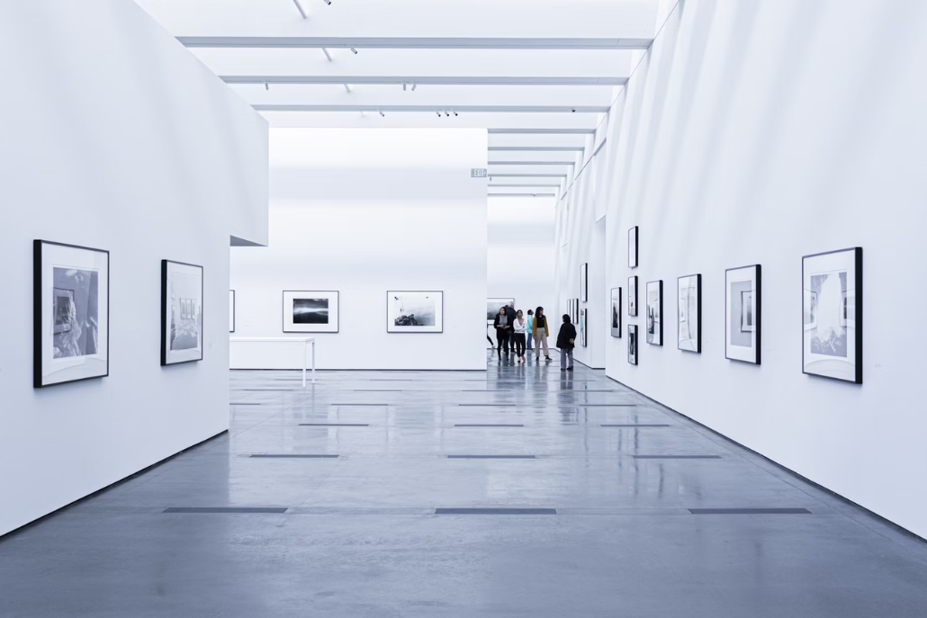 A bright, empty white room with framed photographs, representing high-end art galleries related to Aspen's summer activities.