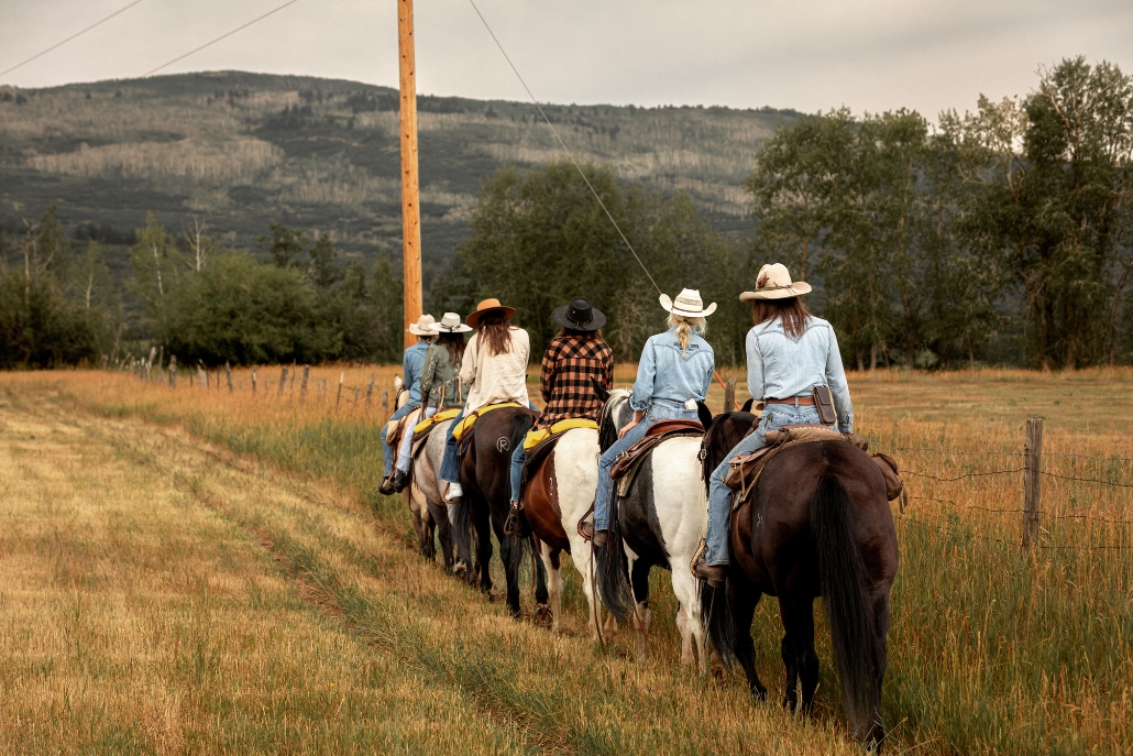 A group of people enjoying horseback riding during Aspen's summer activities in a scenic outdoor setting.