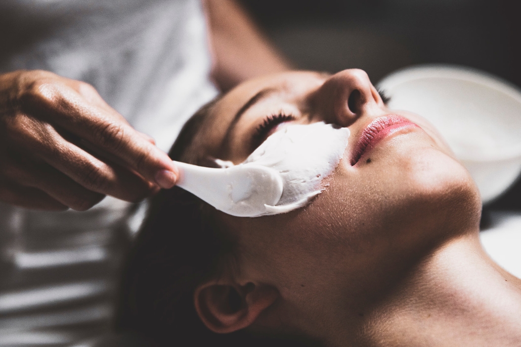A woman undergoing a facial treatment at a luxury spa, with a white sponge gently applied to enhance her skincare.