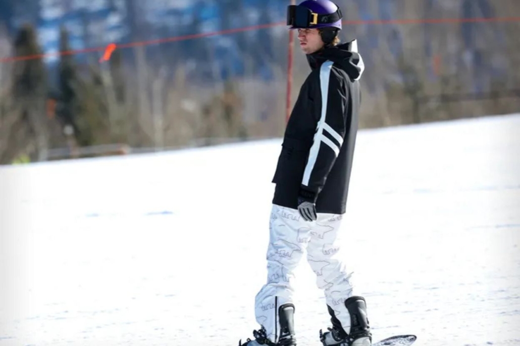 Justin Bieber snowboards on a snowy slope, poised and ready for an exciting ride down the mountain.