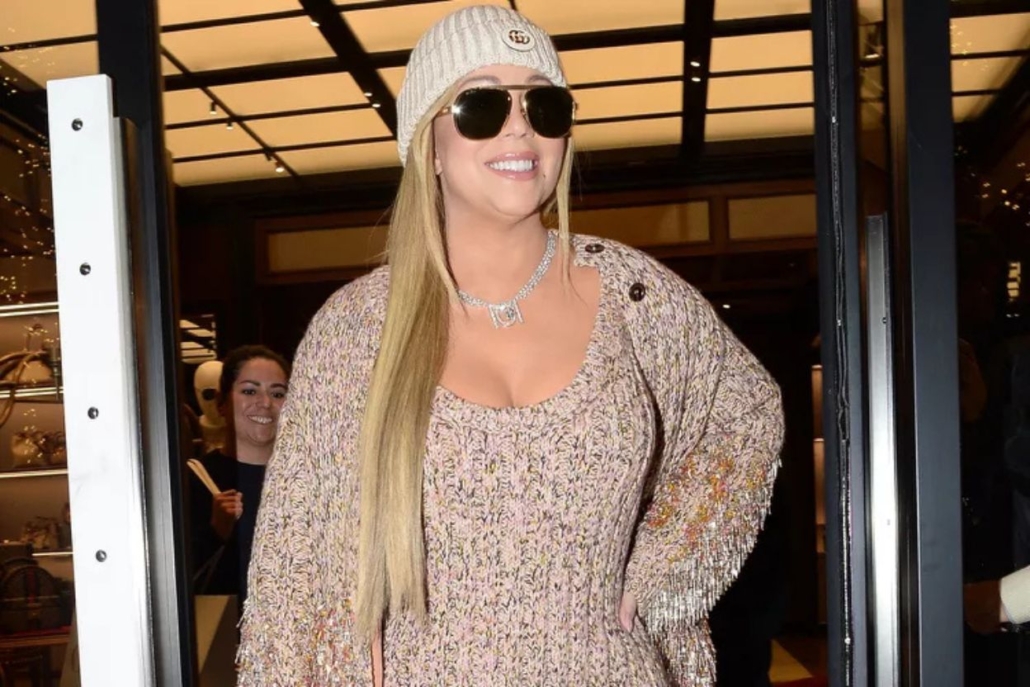 Mariah Carey leaves a store wearing a hat and sunglasses, with a backdrop of Aspen.