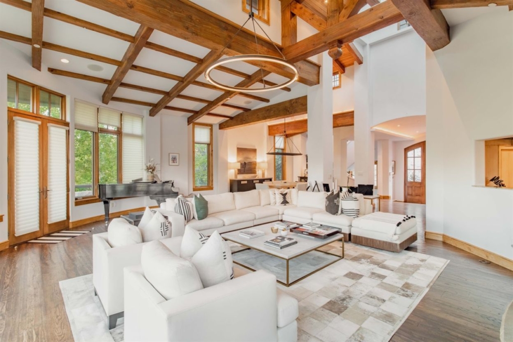 A spacious living room at Spruce Street Retreat featuring wood beams and elegant white furniture.
