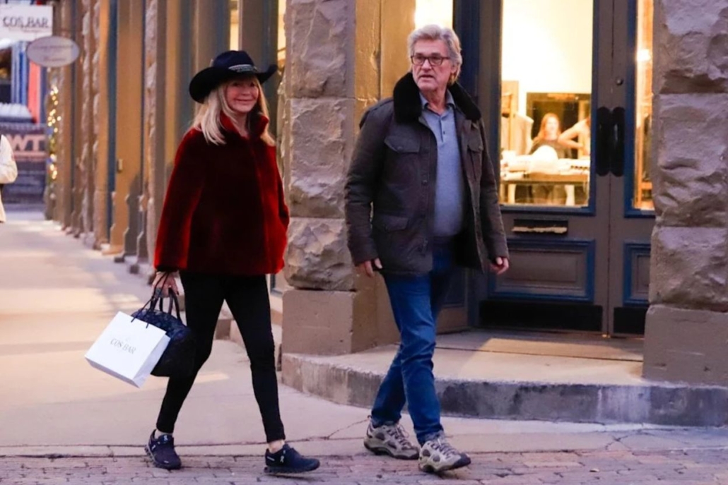 Goldie and Kurt walk side by side on a sidewalk in Aspen, taking in the scenery.