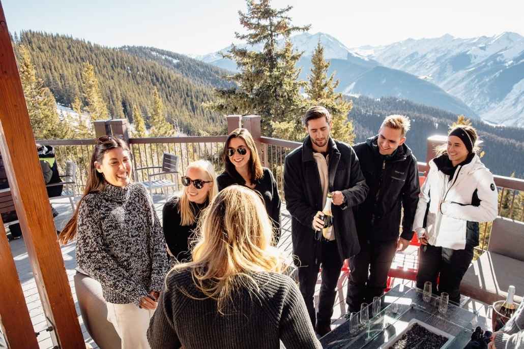 Friends celebrating on a snowy mountain deck in Aspen with champagne.