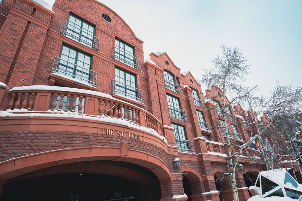The St. Regis Aspen hotel with snow-covered balconies and trees, showcasing its luxurious winter accommodations.