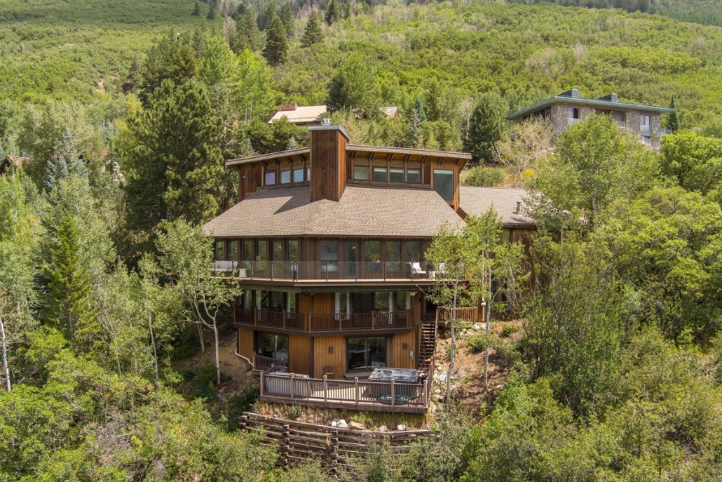 A grand house set against a backdrop of fall trees and mountains, showcasing the beauty of Aspen at Valley Vista Retreat.