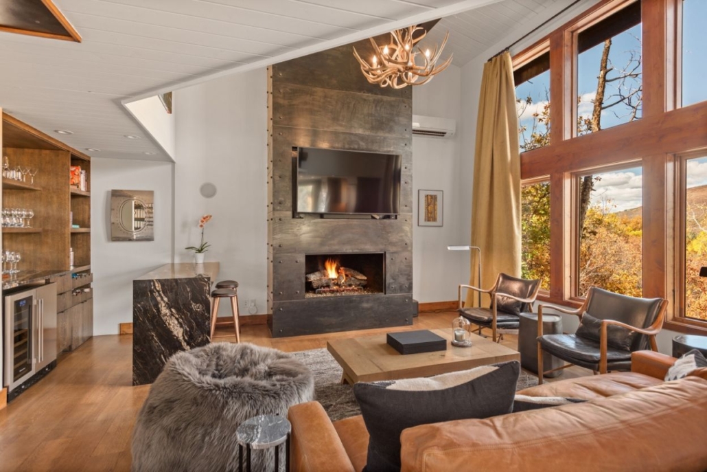 Modern lodge interior with fireplace, bar, and mountain views at Ajax Alpine Lodge in Aspen.