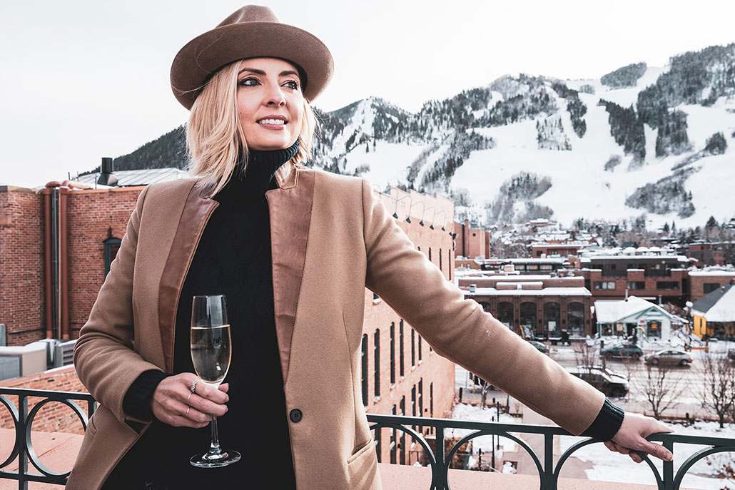 A newlywed woman enjoying cocktail on rooftop deck in Aspen on her honeymoon.