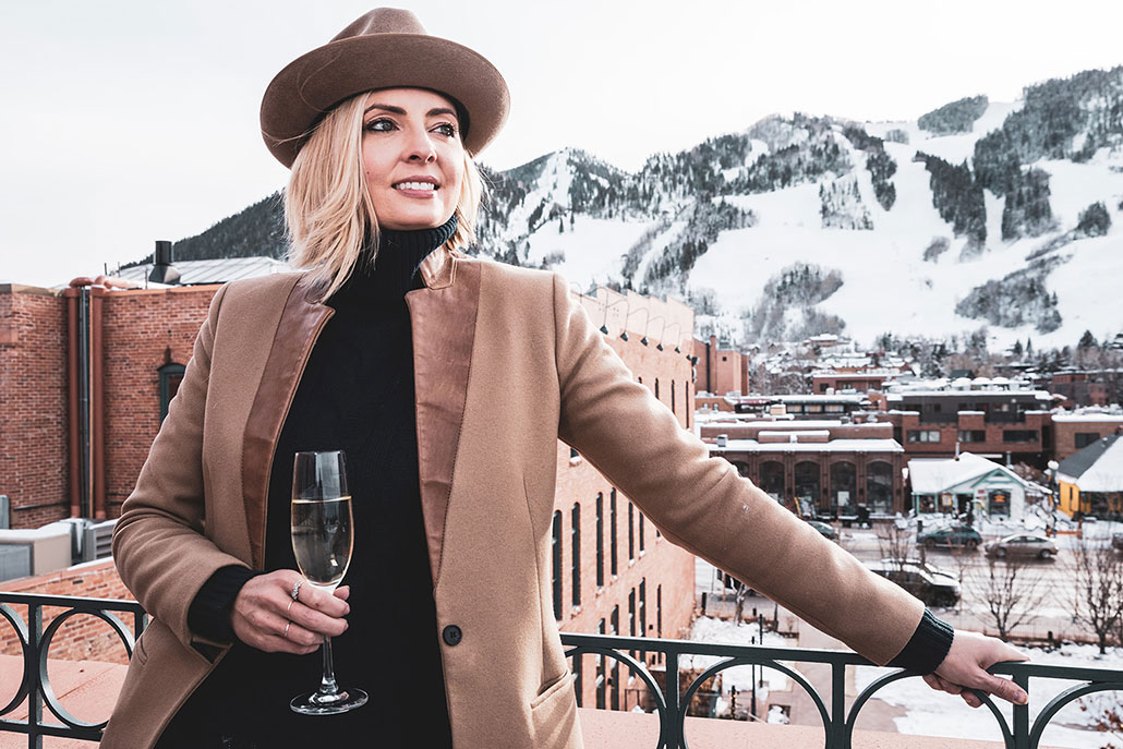 A newlywed woman enjoying cocktail on rooftop deck in Aspen on her honeymoon.