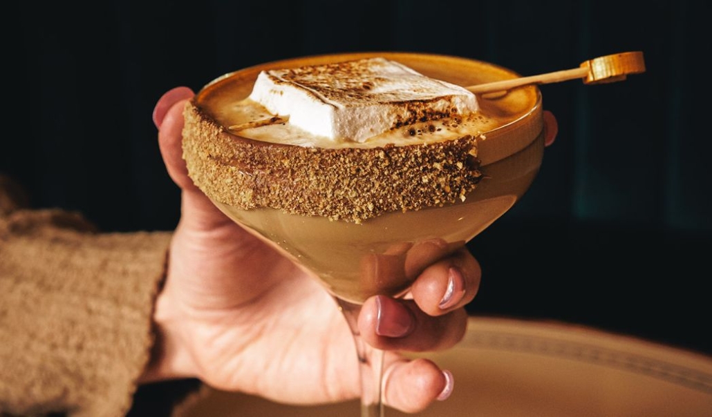 Hand-crafted dessert cocktail topped with a toasted marshmallow and graham cracker rim, perfect for a cozy holiday celebration.