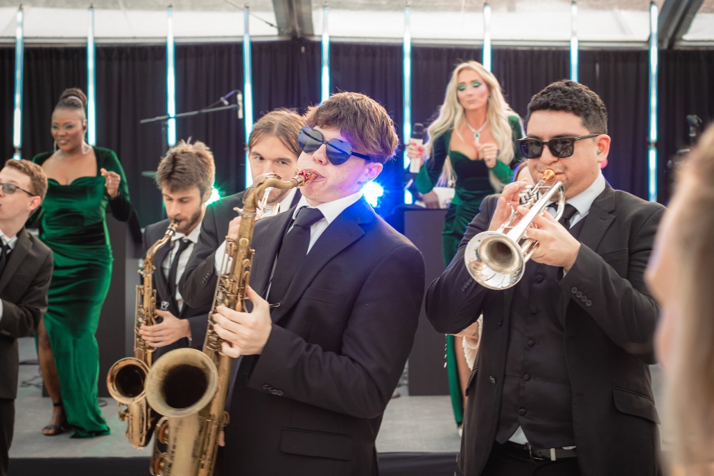 A group of elegantly dressed individuals playing saxophones at the Aspen Party music festival.