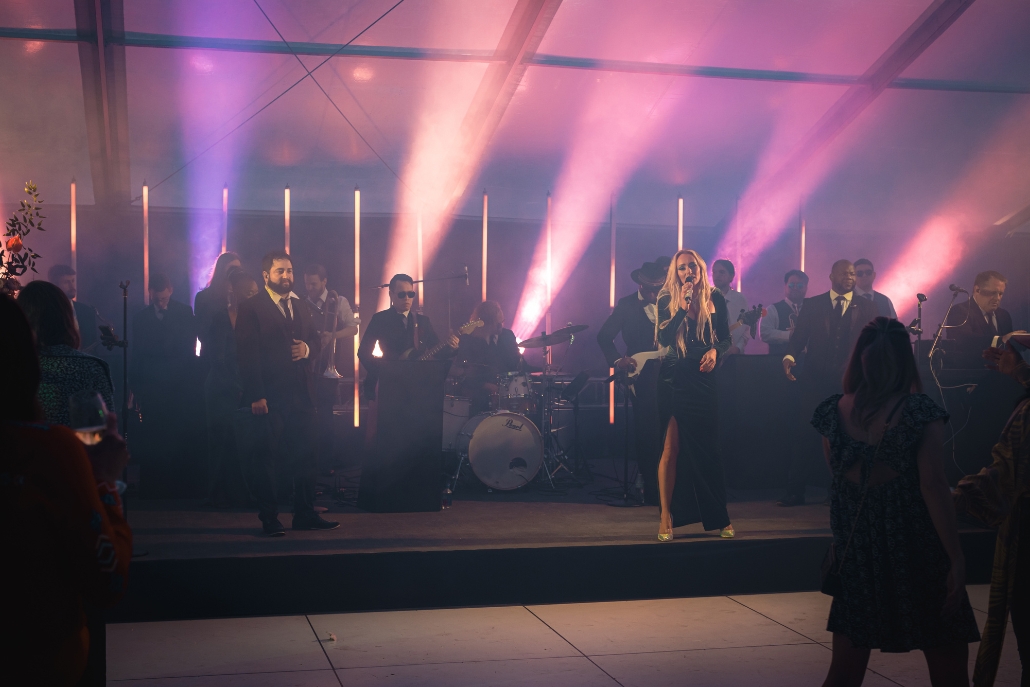 A lively band entertains under vibrant lights in a tent during the Aspen Party Scene event.