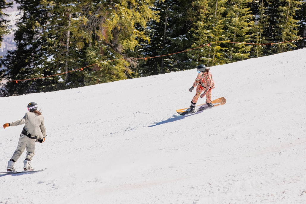 Two people snowboarding on a snowy terrain in Aspen, capturing the essence of winter sports adventures.