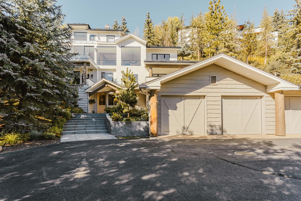 A mountain home featuring a driveway and garage, showcasing accommodation options for Aspen Gay Ski Week.