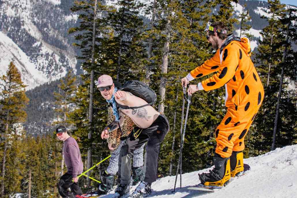 A man in a colorful costume at Aspen Gay Ski Week, showcasing festive attire and a joyful expression.