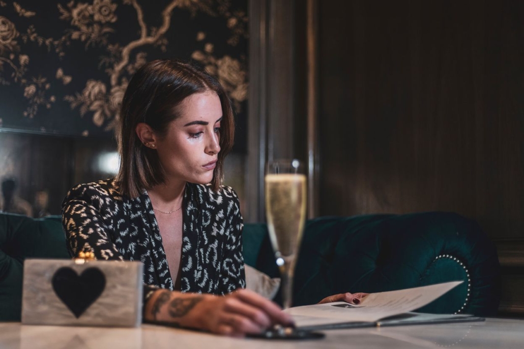 Woman enjoying a quiet après-ski moment with a glass of champagne in an upscale Aspen lounge, seated in a velvet chair with elegant decor.