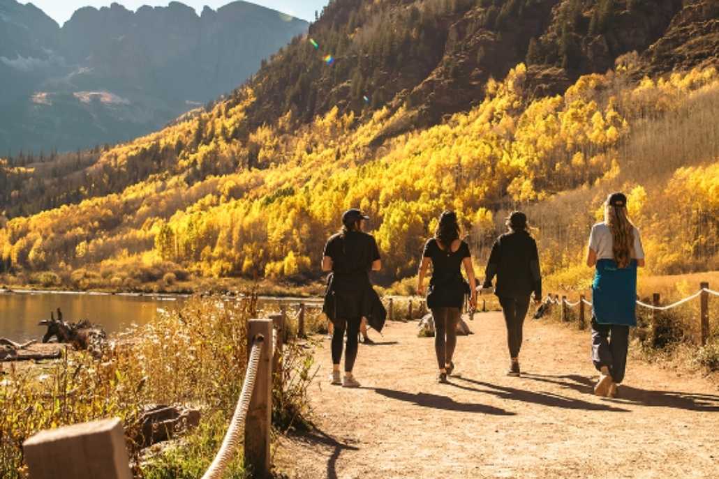 Four hikers walking along a mountain path during an afternoon hike in Aspen, surrounded by scenic views.