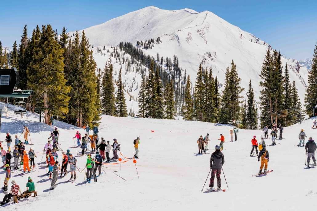 A large group of skiers navigating snowy terrain during Day 3 of the Aspen itinerary at Highlands.