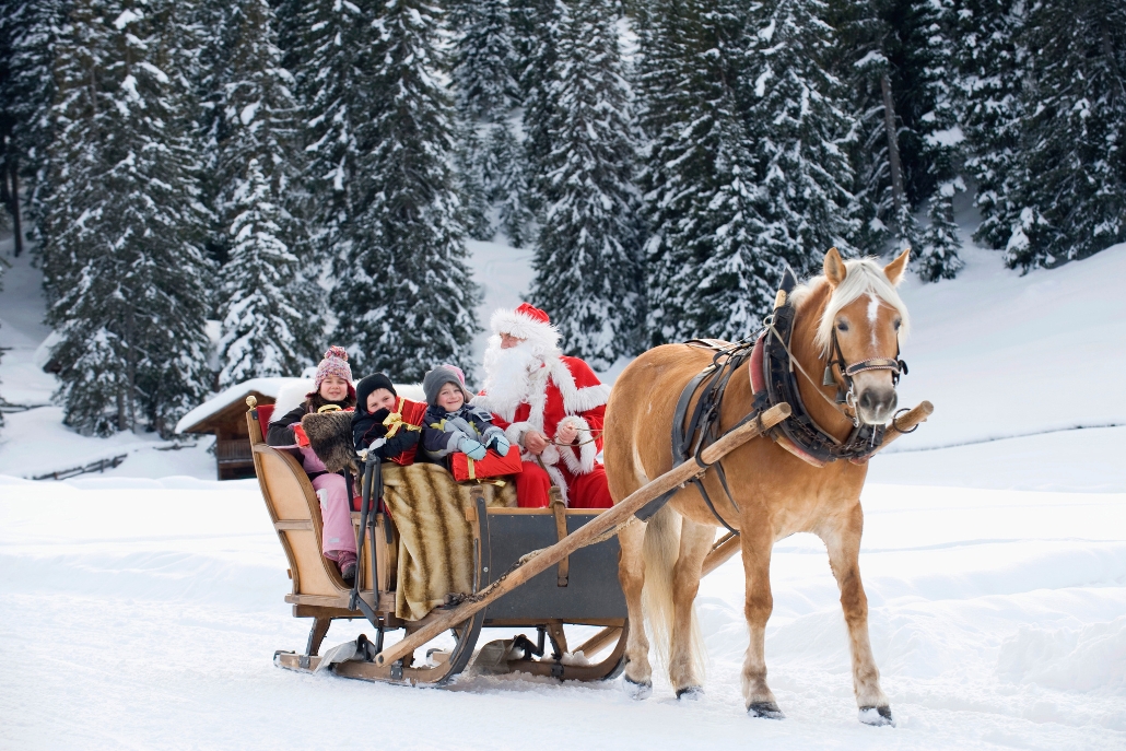 Family riding in a horse-drawn sleigh with Santa Claus during Christmas in snowy Aspen Colorado