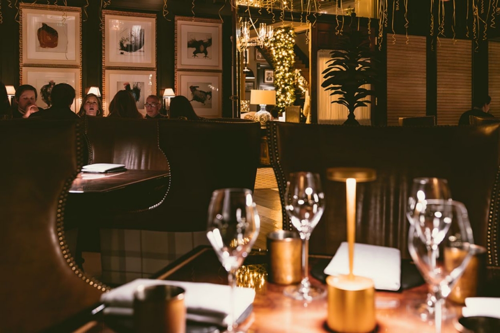 New Year’s Eve dinner at an elegant restaurant with candlelit tables, wine glasses, festive decorations, and guests enjoying a cozy, upscale atmosphere.