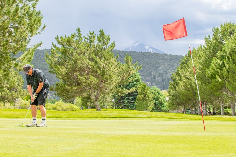 Golfer putting on a scenic golf course in Aspen Colorado with mountain views in the background