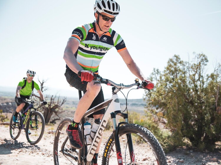 ASPEN SUMMER ACTIVITIES - Biking A man on a bicycle navigates a picturesque route, embodying the outdoor adventure in Aspen