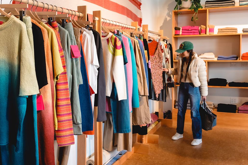 Person browsing colorful clothes in a boutique, holding a shopping basket in Aspen in summer