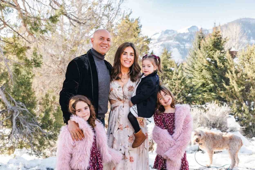 A family poses together in the snow, smiling, during their vacation in Aspen.