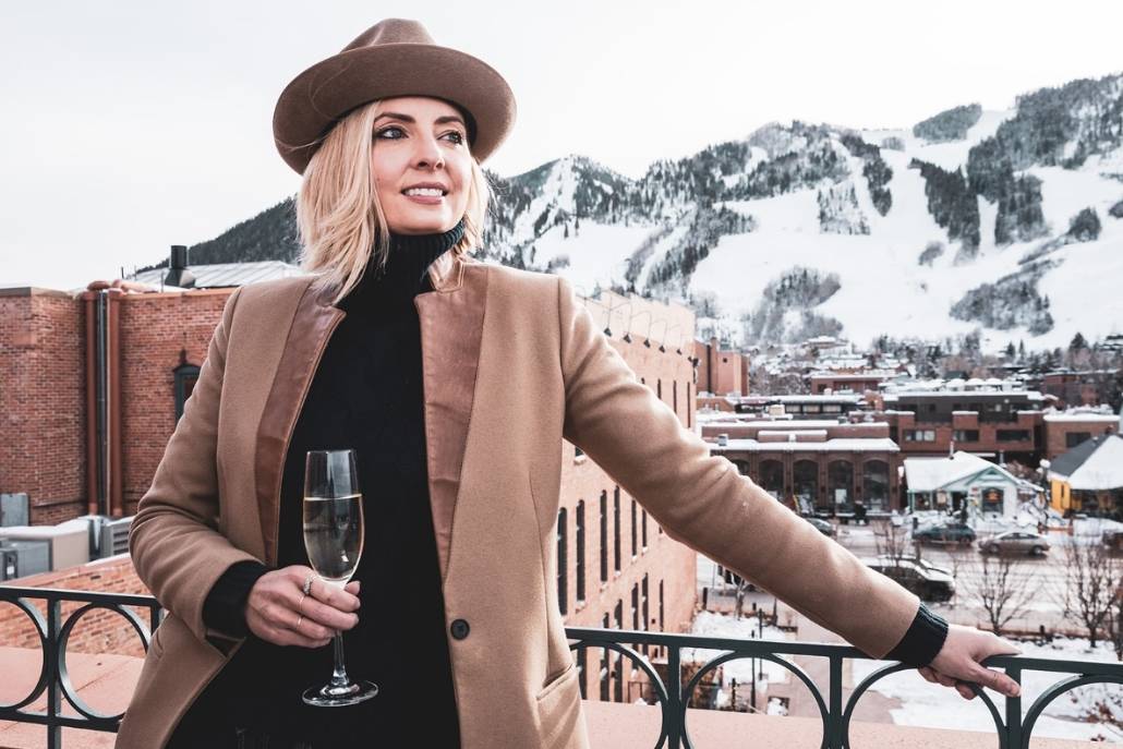Woman enjoying champagne overlooking snowy downtown Aspen during a luxury winter itinerary