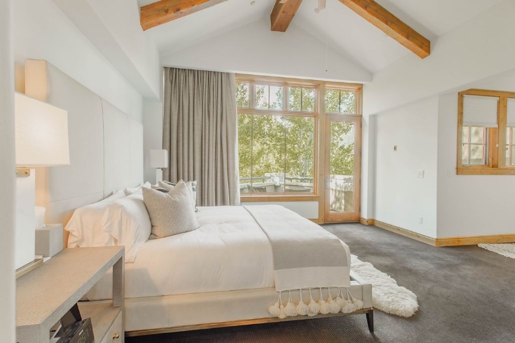 Luxury Aspen bedroom with vaulted beams, large windows, and a private balcony Aspen Visitors Guide