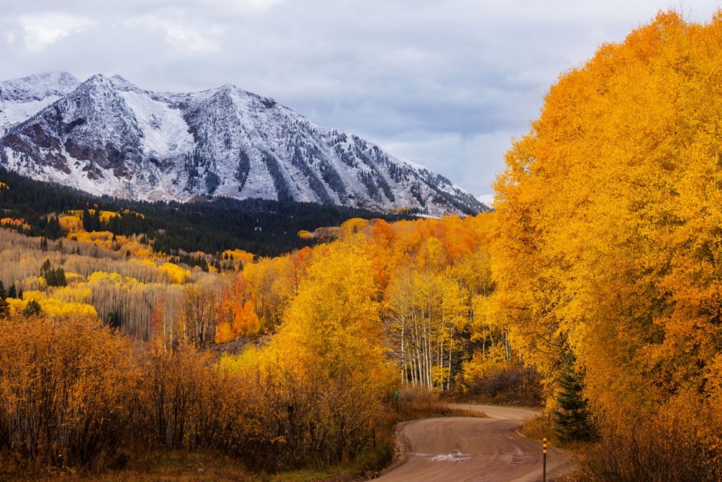 Snow-covered mountains and golden fall foliage in Aspen during October.